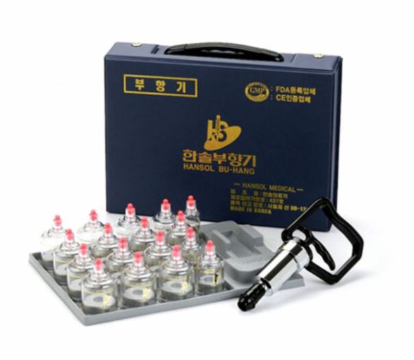 A 17-piece Hansol Professional Cupping and Massage Set displayed with various sized clear cups arranged on a metal tray and a black pistol hand pump, all placed inside a blue carrying case with Korean text.